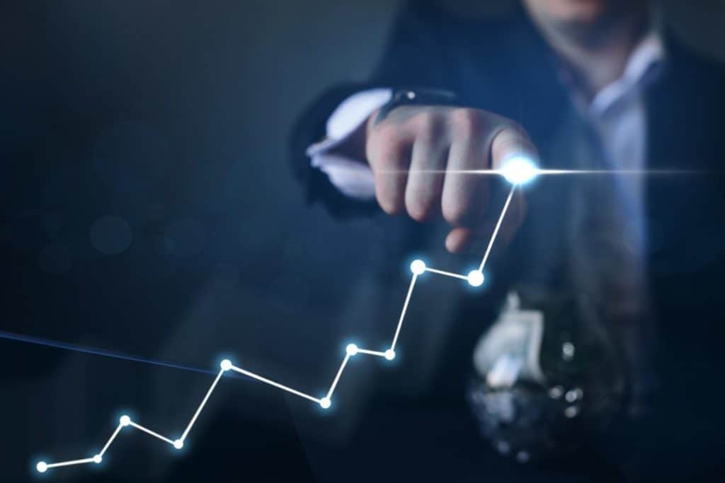 business growth and sales increase man using finger to draw line chart with light